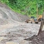Alat berat Beko membersihkan jalan nasional di Desa Loji dari material longsor susulan. (Prima Arno/Telusur Bisnis)