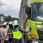 Petugas menghentikan truk sumbu tiga yang nekat tetap beroperasi di exit tol Parungkuda. (Prima Arno/Telusurbisnis)