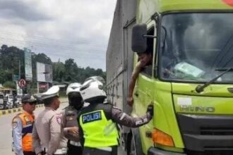 Petugas menghentikan truk sumbu tiga yang nekat tetap beroperasi di exit tol Parungkuda. (Prima Arno/Telusurbisnis)