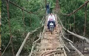 Jembatan Gantung Jantake yang akan diperbaiki. Tampak seorang warga nekat menyeberangi jembatan dengan motor. (Prima Meidiandi/Telusurbisnis)