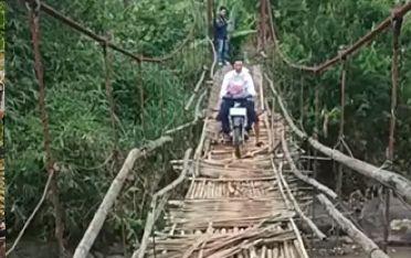 Jembatan Gantung Jantake yang akan diperbaiki. Tampak seorang warga nekat menyeberangi jembatan dengan motor. (Prima Meidiandi/Telusurbisnis)